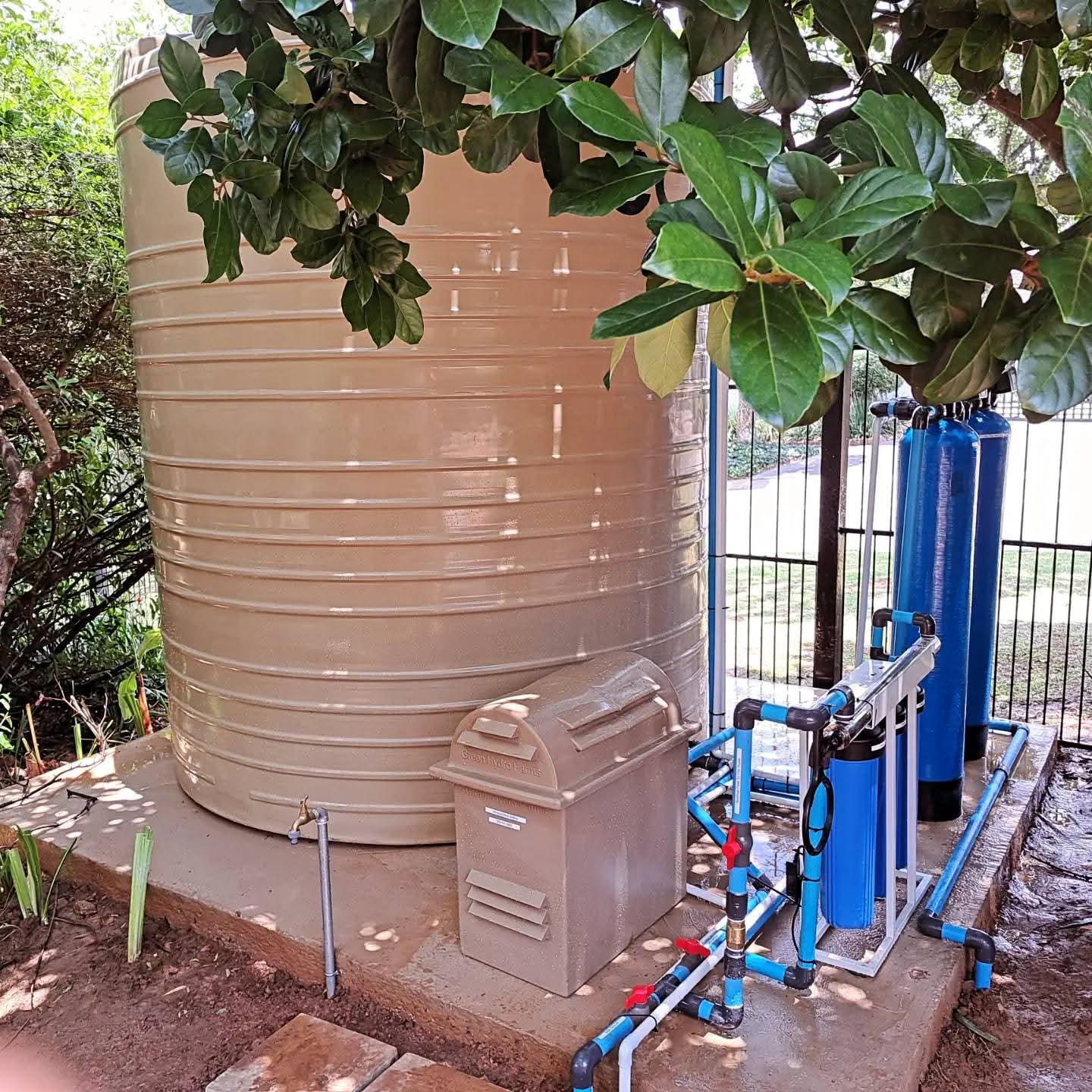 Completed BoreFixPro reticulation installation with cream storage tank, pump housing and blue filtration vessels in a residential garden